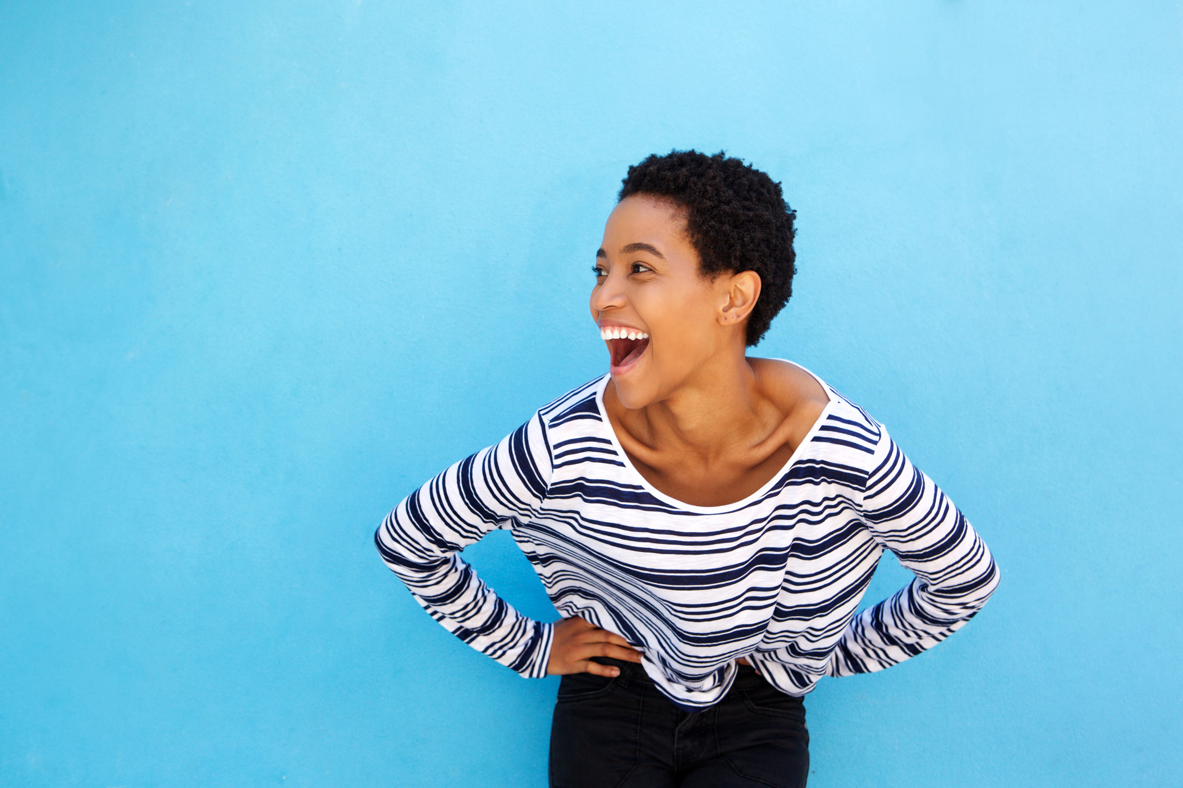 Happy Young Black Woman Laughing against Blue Background